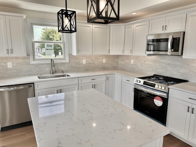 kitchen featuring backsplash, light wood-style flooring, appliances with stainless steel finishes, white cabinetry, and a sink