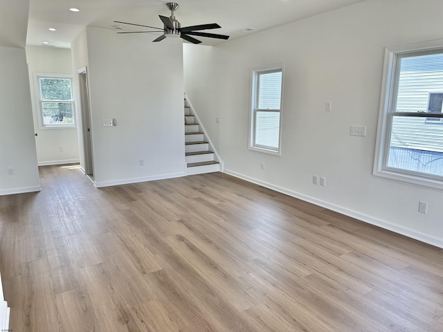 unfurnished living room featuring a ceiling fan, wood finished floors, recessed lighting, baseboards, and stairs