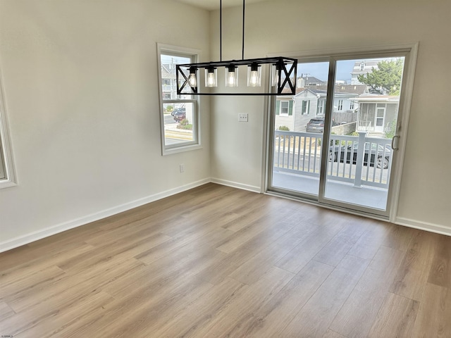 unfurnished dining area featuring baseboards and wood finished floors