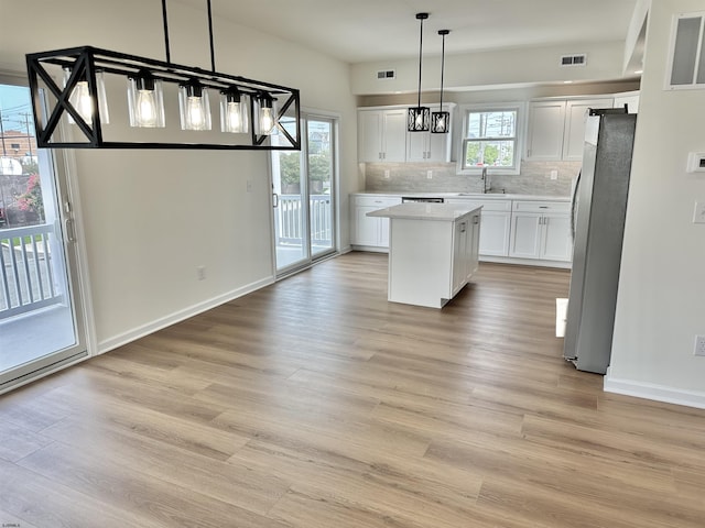 kitchen with white cabinets, tasteful backsplash, visible vents, and freestanding refrigerator