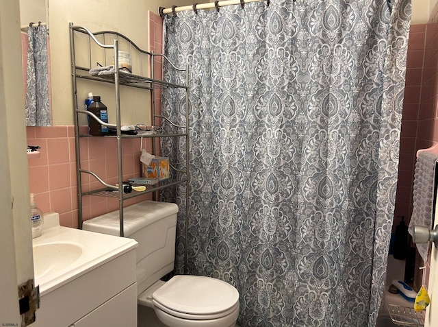 bathroom featuring a shower with shower curtain, vanity, toilet, and tile walls