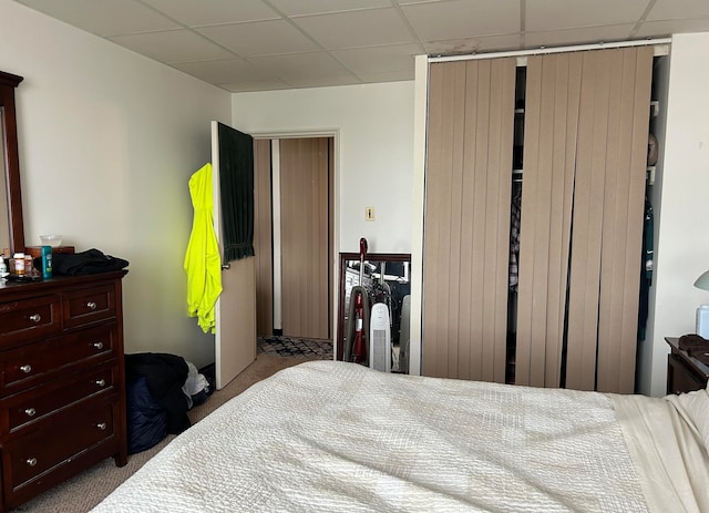 carpeted bedroom featuring a closet and a drop ceiling