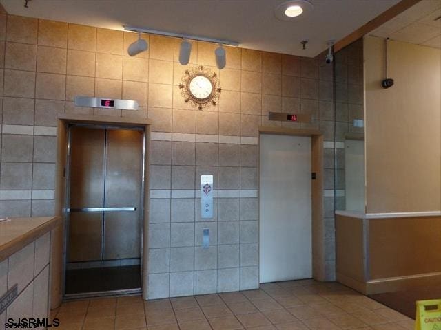 bathroom featuring tile walls, elevator, and tile patterned floors