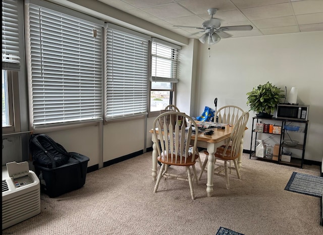 carpeted dining room featuring ceiling fan and a drop ceiling