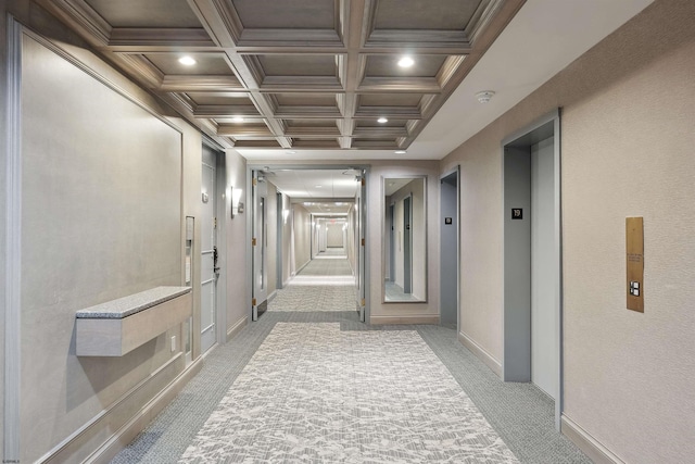 hallway featuring coffered ceiling, beamed ceiling, light carpet, and elevator