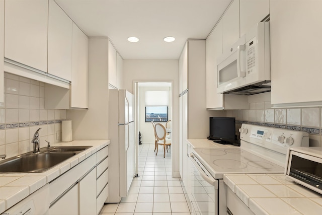 kitchen featuring light tile patterned flooring, white appliances, white cabinetry, and sink