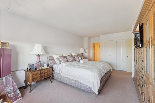 bedroom featuring light colored carpet and multiple closets