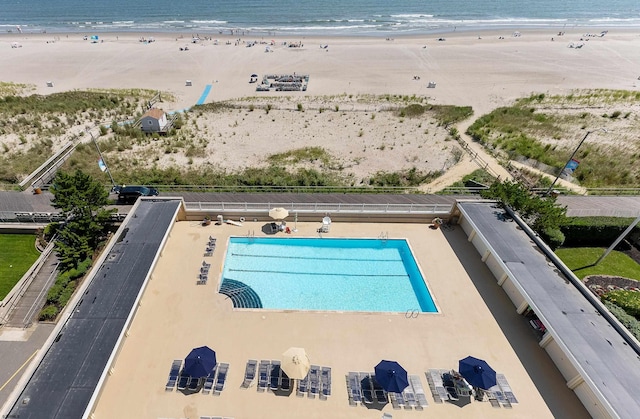 view of swimming pool with a water view and a beach view