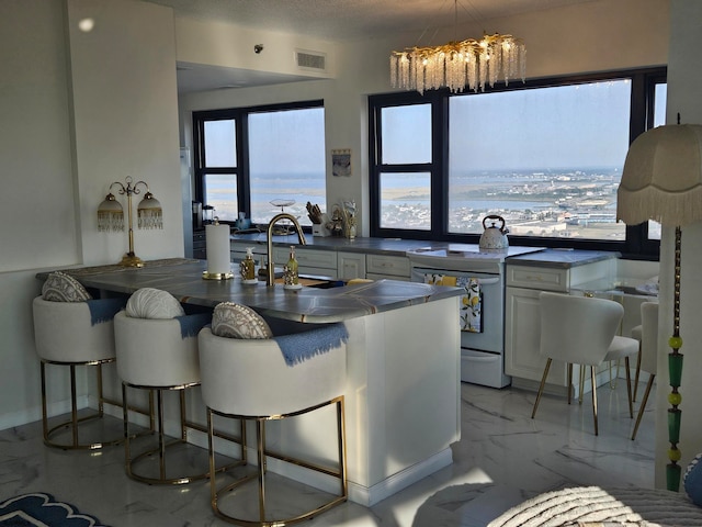 kitchen featuring white stove, an inviting chandelier, and white cabinets