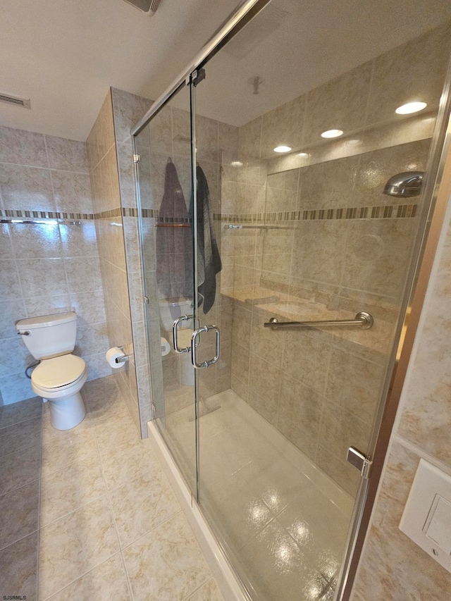 bathroom with tile walls, toilet, tile patterned floors, and walk in shower