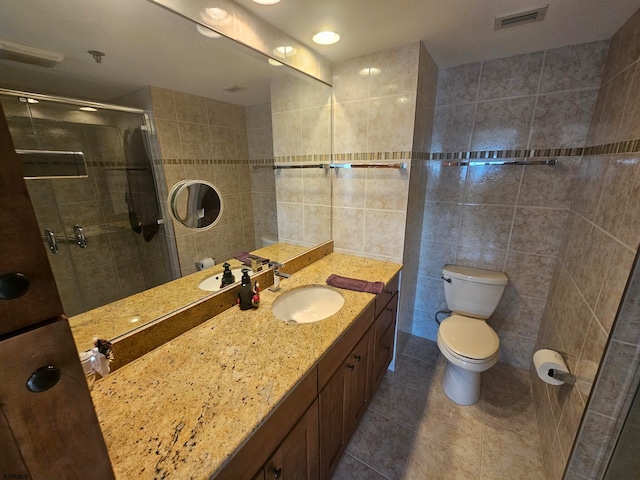 bathroom featuring tile patterned floors, walk in shower, toilet, tile walls, and vanity