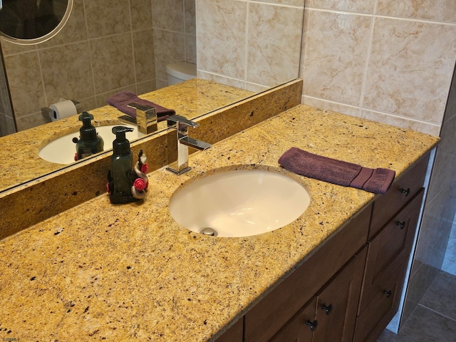 bathroom featuring vanity, toilet, and tile walls