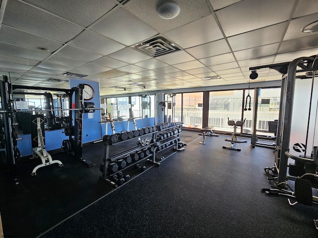 exercise room with a healthy amount of sunlight and a drop ceiling