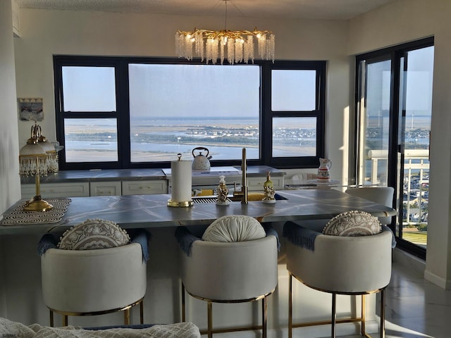 tiled dining space with a wealth of natural light, a notable chandelier, and a water view