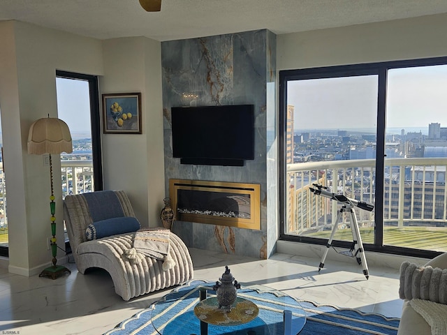 living room with a high end fireplace, a textured ceiling, and ceiling fan