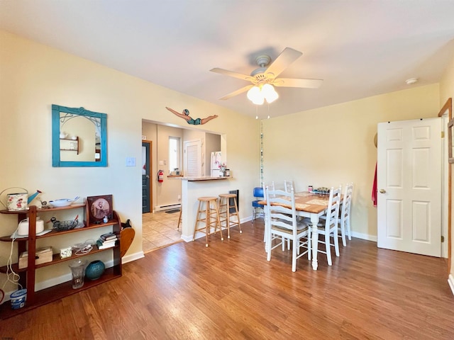 dining space featuring a baseboard heating unit, ceiling fan, and light wood-type flooring