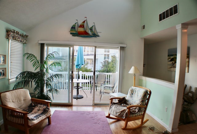 living area featuring vaulted ceiling, ornate columns, and light hardwood / wood-style floors