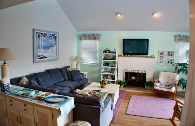 living room featuring a fireplace, vaulted ceiling, and light hardwood / wood-style floors