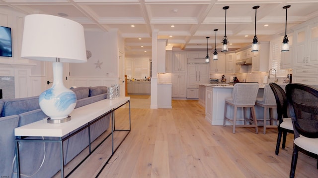 kitchen featuring light stone countertops, tasteful backsplash, hanging light fixtures, white cabinetry, and light wood-type flooring