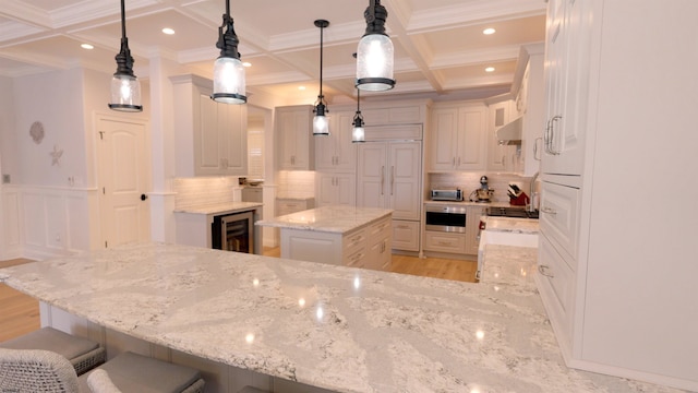 kitchen with a kitchen island, decorative light fixtures, light stone countertops, beverage cooler, and backsplash