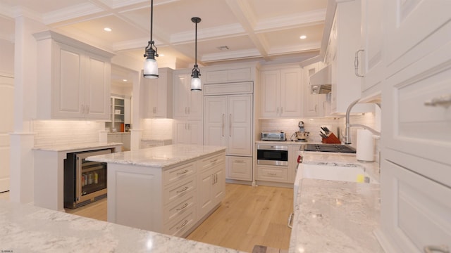 kitchen featuring light stone counters, white cabinetry, coffered ceiling, beverage cooler, and pendant lighting