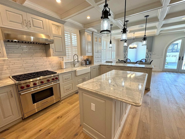 kitchen featuring a kitchen island, coffered ceiling, premium stove, sink, and light wood-type flooring