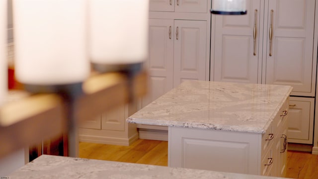 kitchen featuring light stone countertops, white cabinetry, and light hardwood / wood-style floors