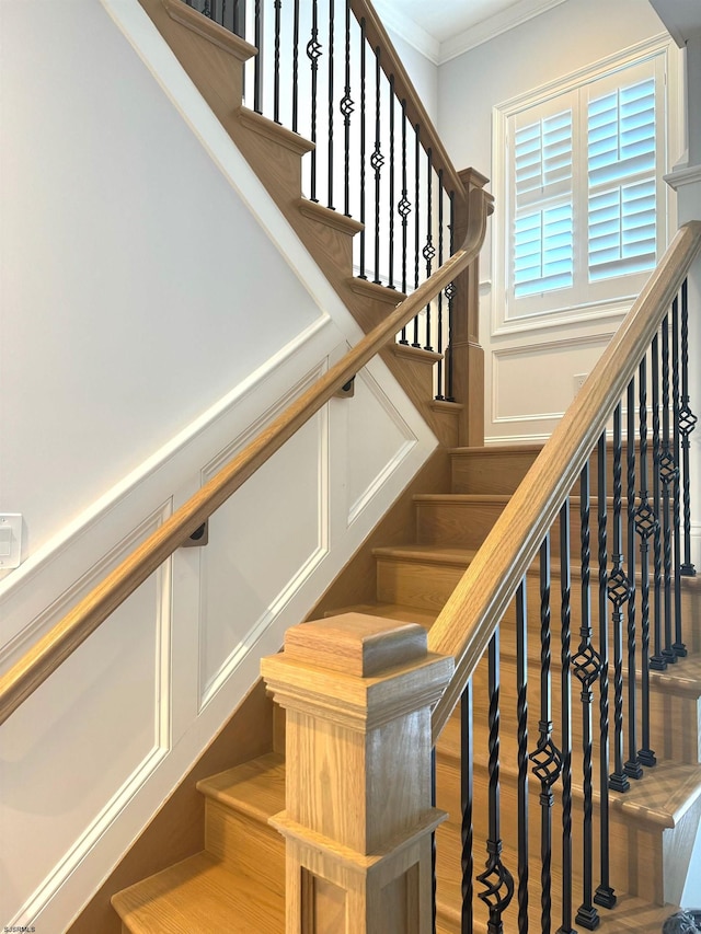 stairs with ornamental molding and wood-type flooring