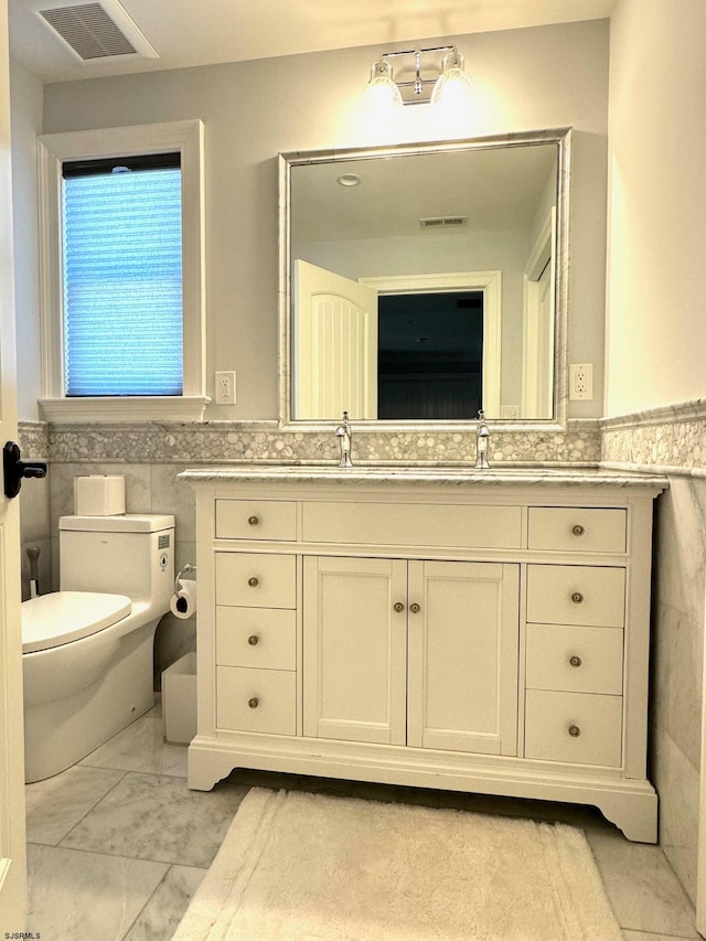 bathroom with tile walls, toilet, and vanity