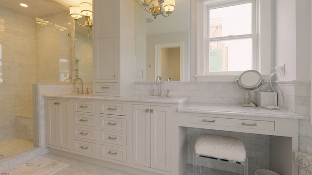 bathroom featuring a notable chandelier, tile patterned flooring, vanity, a tile shower, and tile walls