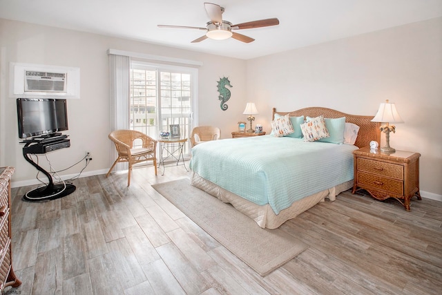 bedroom with an AC wall unit, light hardwood / wood-style floors, and ceiling fan