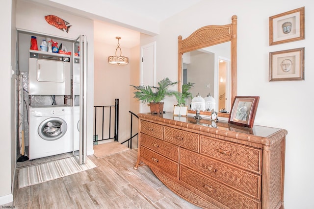 laundry room featuring hardwood / wood-style floors and stacked washing maching and dryer