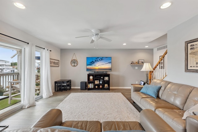 living room with light wood-type flooring, ceiling fan, and plenty of natural light