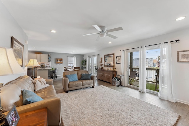 living room with light wood-type flooring and ceiling fan