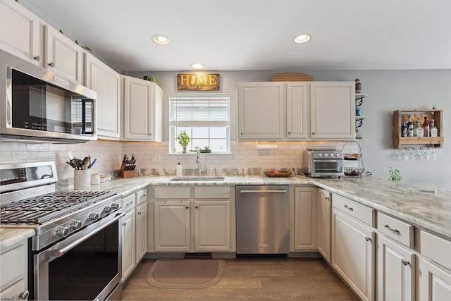 kitchen with stainless steel appliances, white cabinetry, and sink