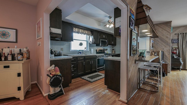 kitchen with appliances with stainless steel finishes, decorative backsplash, light wood-type flooring, and ceiling fan