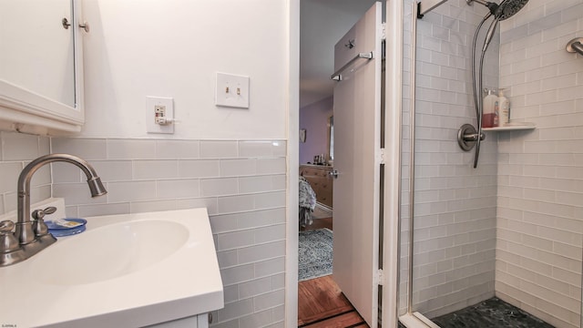 bathroom featuring vanity, tile walls, a tile shower, and hardwood / wood-style flooring