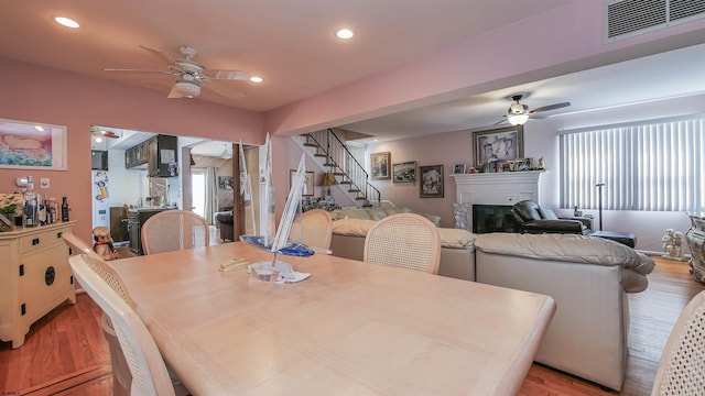 dining area with ceiling fan, a fireplace, and light hardwood / wood-style floors