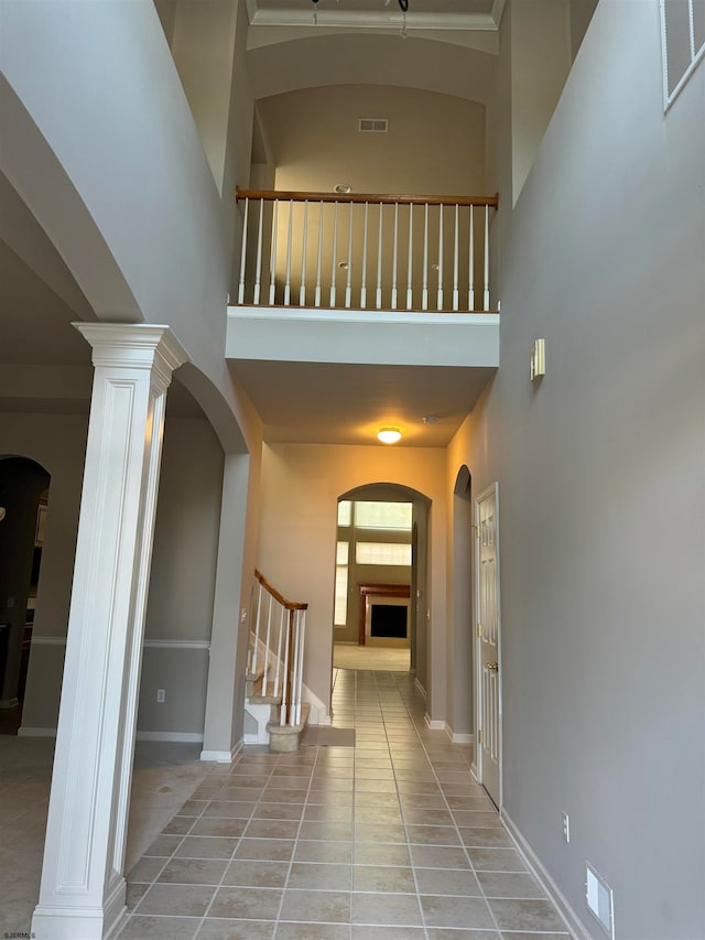 hall featuring ornate columns, light tile patterned flooring, and a high ceiling