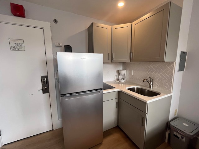 kitchen with stainless steel fridge, backsplash, dark hardwood / wood-style flooring, gray cabinets, and sink