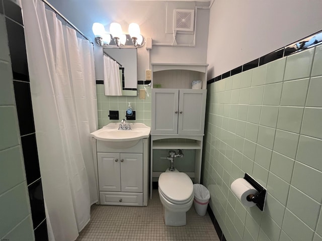 bathroom with tile walls, tile patterned floors, vanity, and toilet