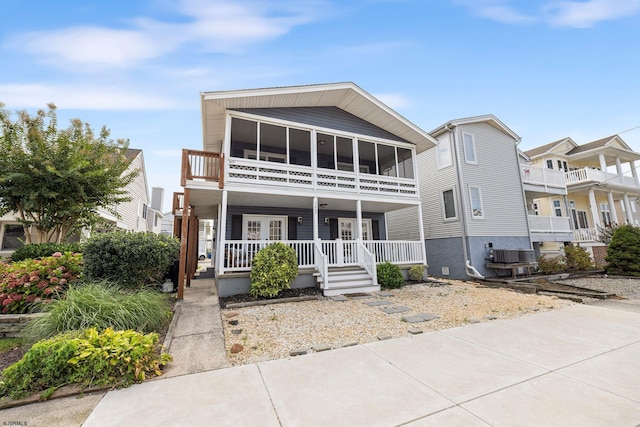 view of front facade featuring a balcony, a porch, a sunroom, and central AC