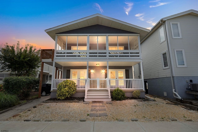 view of front of home with a sunroom, a porch, and central air condition unit