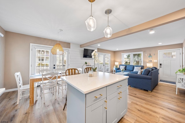 kitchen featuring a kitchen breakfast bar, light wood-type flooring, hanging light fixtures, and a kitchen island