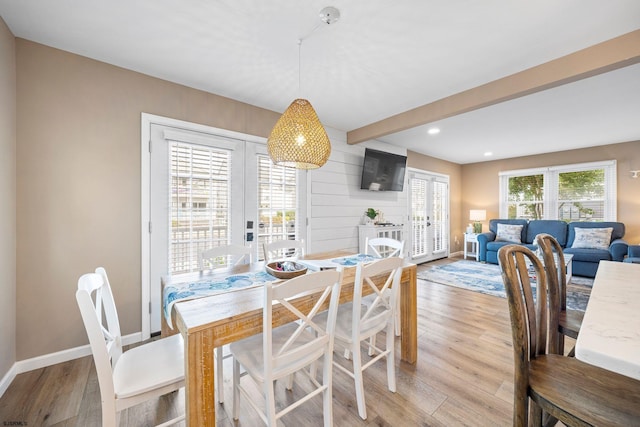 dining area with french doors, wooden walls, and light hardwood / wood-style floors