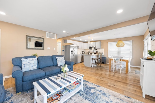 living room with light hardwood / wood-style floors and a healthy amount of sunlight