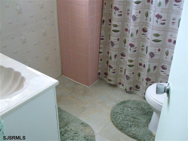 bathroom with tile patterned flooring, curtained shower, vanity, and toilet