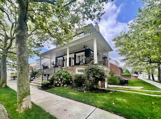 view of front of property with ceiling fan, a front yard, and covered porch