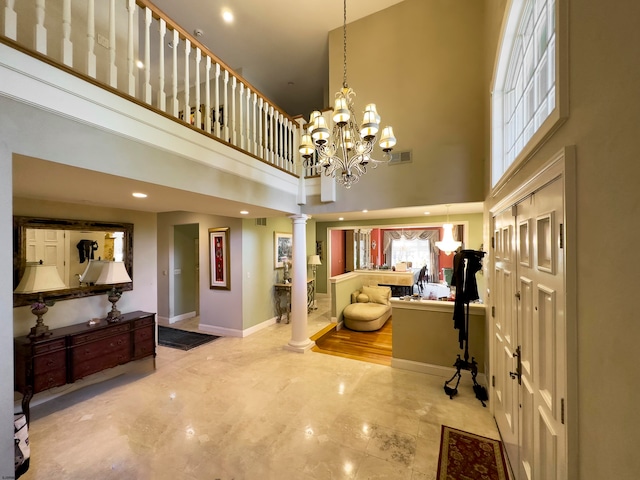 foyer with an inviting chandelier, a towering ceiling, and decorative columns