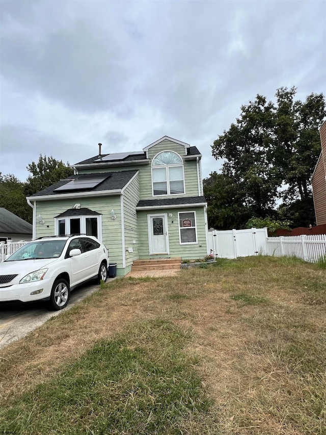 view of front facade featuring a front lawn and solar panels